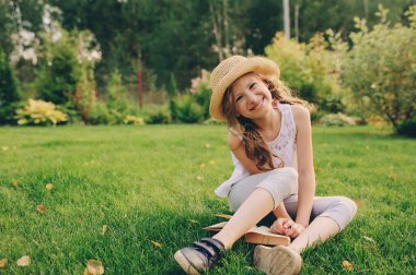 Çocuk yaz tatillerinde kitap okuyor, yeşil çimenler ve güneşli sıcak bir gün..