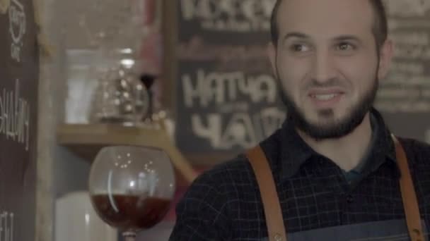 Um jovem homem de barista sorridente dando um café. Câmera lenta — Vídeo de Stock