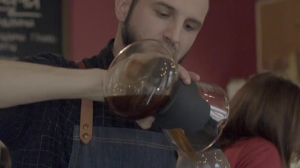 Молодий усміхнений бариста виливає каву з Сифоном — стокове відео