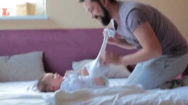 Genç baba evde bebek için bez ve kıyafet değiştiriyor.