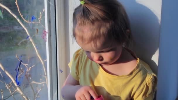 Happy toddler girl with paint on hands near the window. Kid at home concept. Quarantine — Stock Video