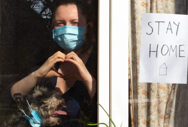 Evde kal. Koruyucu flüt maskeli bir kadın ve tıbbi maskeli bir köpek..
