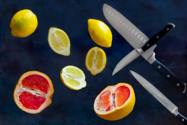 Citrons, pamplemousses et couteaux de cuisine volent dans l'air. Concept de lévitation alimentaire — Photo