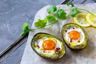 Keto diyet yemeği: Yumurtalı, limonlu ve kişniş soslu avokado tekneleri. Gri arkaplan, boşluğu kopyala