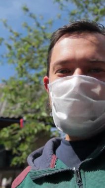 Koruyucu maske takmış sakallı bir adamın el kamerası görüntüsü ve video görüşmesinde uzayan bir elin görüntüsü. Coronavirus salgını, 2019-nCoV Covid-19.