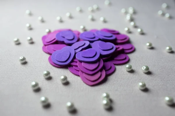 Пурпурные сердца и жемчуг, лежащие на бежевой ткани — стоковое фото