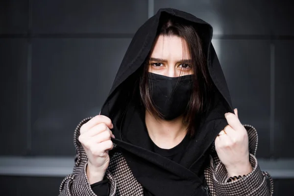 Young woman wearing face mask. Handsome woman in black hoodie wear black medical mask. Pandemic coronavirus covid-19 quarantine period concept.