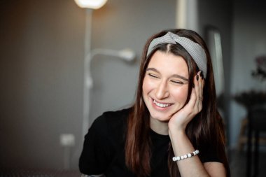 Genç ve güzel bir kız kendini tecrit ettiği sırada bir dairede. Üzerinde siyah elbiseler ve kafasında bir bandana var.