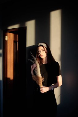 Genç ve güzel bir kız kendini tecrit ettiği sırada bir dairede. Üzerinde siyah elbiseler ve kafasında bir bandana var.