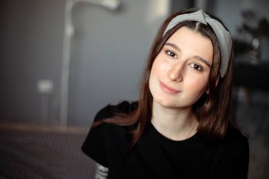 Genç ve güzel bir kız kendini tecrit ettiği sırada bir dairede. Üzerinde siyah elbiseler ve kafasında bir bandana var.