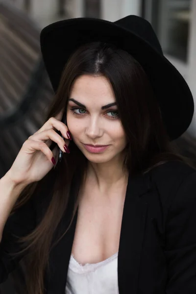 Une femme portant un chapeau noir et utilisant un téléphone portable — Photo