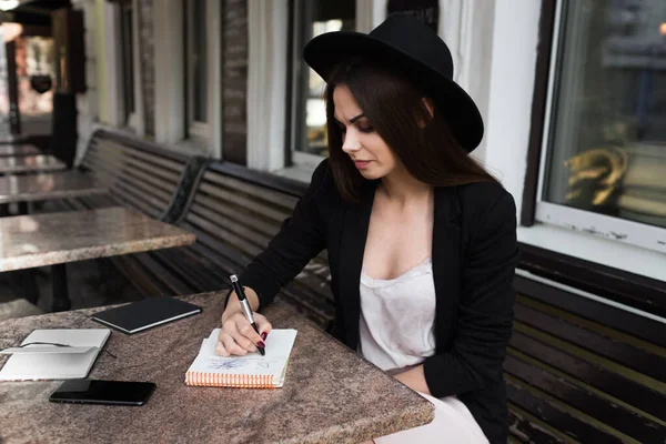 A young girl writer writes articles for a fashion magazine on a summer verand