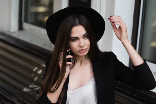 Une femme portant un chapeau noir et utilisant un téléphone portable — Photo