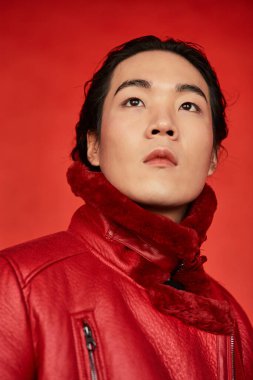 Kırmızı arka planda Asyalı bir adam var.