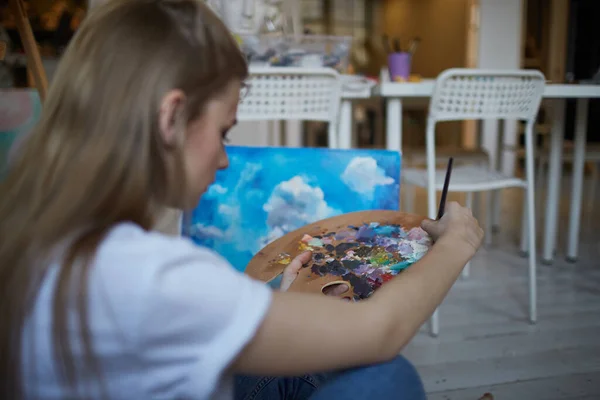 A palette of paints in the hands of a girl