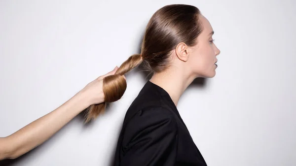 Ruka drží ocas vlasů na bílém pozadí. — Stock fotografie