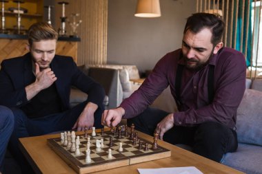 Erkekler modern bir tasarıma sahip şık bir çatı katında satranç oynarlar.