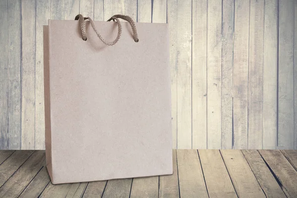 Isolated recycled paper shopping bag. Wooden background. Empty copy space