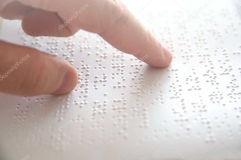 Hand of a blind person reading some braille text touching the relief. Empty copy space