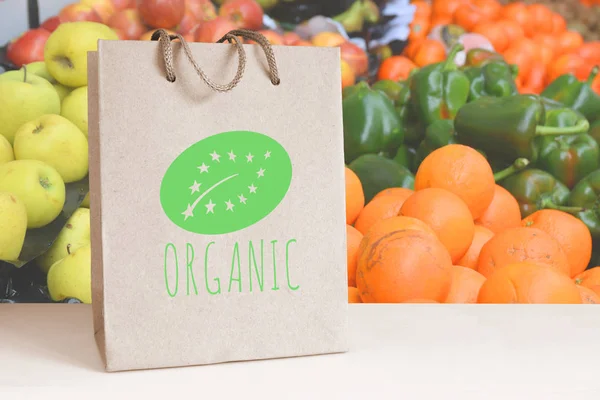 Recicled paper bag with the ORGANIC word and logo. Some natural fruits and vegetables. Empty copy space