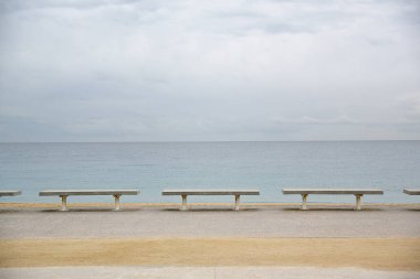 Satırı banklar denizin yanında. Bulutlu gökyüzü mavi. Boş kopya alanı