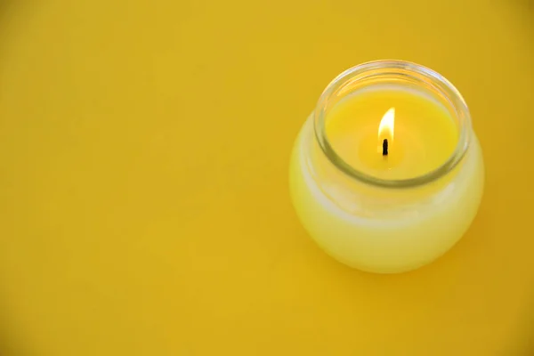 Sarı minimalist merkezinde bir citronella mum bir cam. Boş kopya alanı