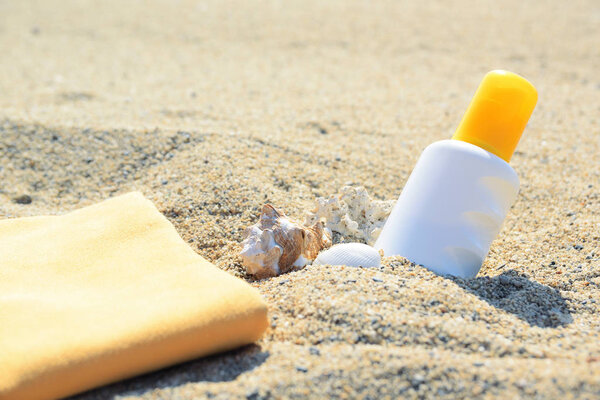 Sunscreen tube on the sand next to the beach. Empty copy space