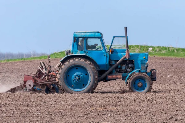 Un vieux tracteur laboure la terre. Paysage printanier d'une campagne, une ferme . — Photo