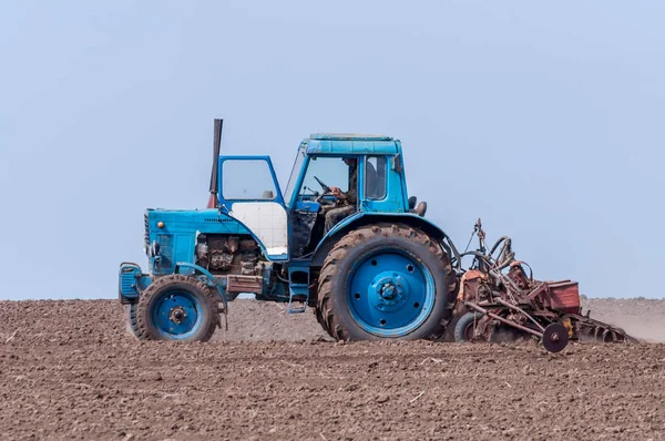 Un vieux tracteur laboure la terre. Paysage printanier d'une campagne, une ferme . — Photo