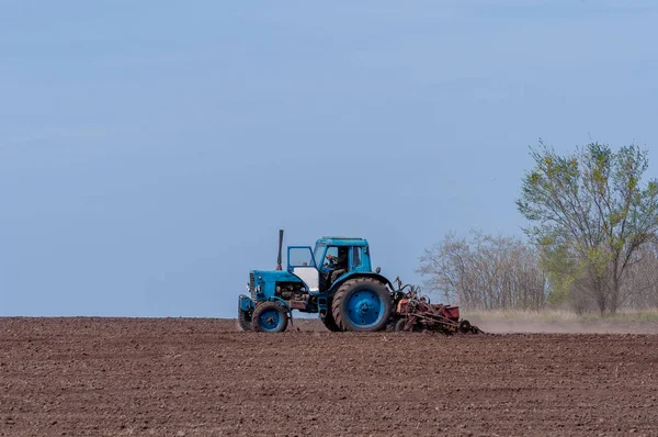 Un vieux tracteur laboure la terre. Paysage printanier d'une campagne, une ferme . — Photo