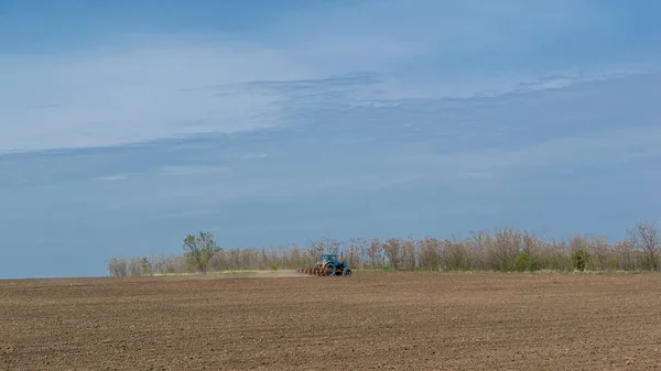 Un vieux tracteur laboure la terre. Paysage printanier d'une campagne, une ferme . — Photo