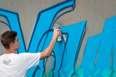 Ukrayna, Nikolaev, 24.06.2017: Festival grafiti gençlik günlük ayrılmış. Şehir merkezi kare. Genç çocuk bir sprey ile bir duvara grafiti çizim.