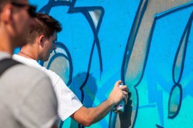 Ukrayna, Nikolaev, 24.06.2017: Festival grafiti gençlik günlük ayrılmış. Şehir merkezi kare. Genç çocuk bir sprey ile bir duvara grafiti çizim.