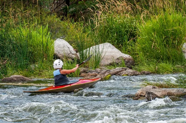 Un adolescente entrena en el arte del kayak. Barcas en rápidos de río. El niño se dedica hábilmente al rafting. . — Foto de Stock