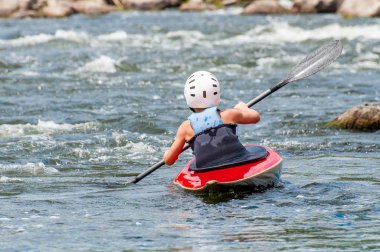 Bir genç Kayak sanatı eğitiyor. Slalom kaba river rapids gemilerde. Çocuk ustaca rafting içinde devreye girer.