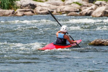 Bir genç Kayak sanatı eğitiyor. Slalom kaba river rapids gemilerde. Çocuk ustaca rafting içinde devreye girer.