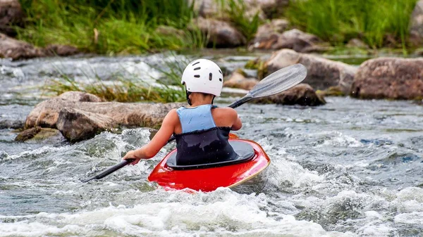 Um adolescente treina na arte de caiaque. Barcos Slalom em corredeiras de rio áspero. A criança está habilmente envolvida em rafting . — Fotografia de Stock