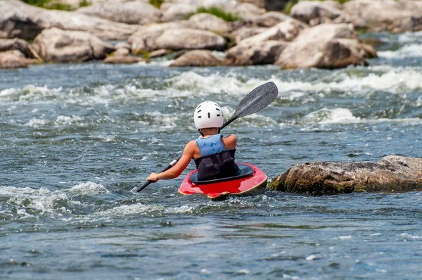 Um adolescente treina na arte de caiaque. Barcos Slalom em corredeiras de rio áspero. A criança está habilmente envolvida em rafting . — Fotografia de Stock