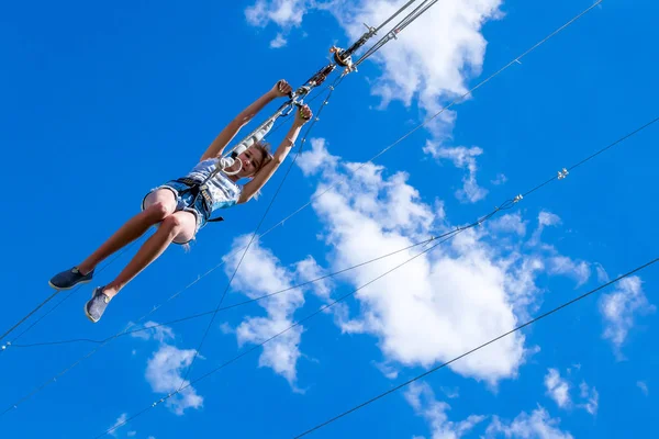 Ucrania, Migea - 30 de junio de 2017: Zipline. Una vista de un hombre deslizándose sobre un cable de acero contra un hermoso cielo azul con nubes blancas. Descanso extremo y activo . — Foto de Stock