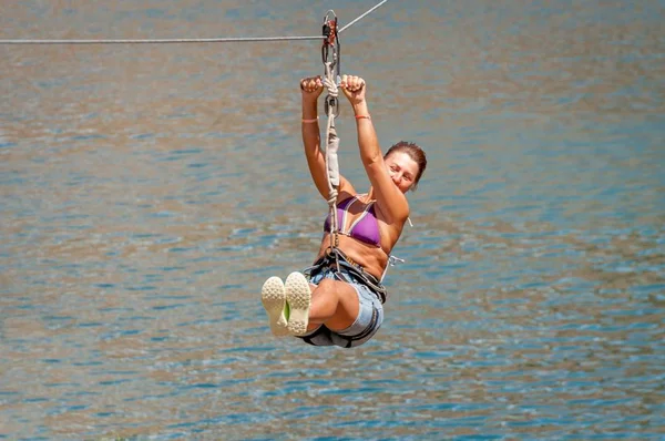 Zipline. La donna nell'attrezzatura scivola su un cavo d'acciaio. Trolley Track Oltre il lago. Riposo estremo e attivo . — Foto Stock