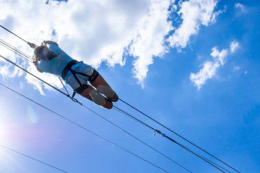 Zipline. Bir adam güzel bir mavi gökyüzü beyaz bulutlar ile karşı çelik kablo üzerinde kayar bir görüntü. Aşırı ve aktif dinlenme.