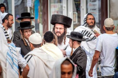 A group of Hasidim pilgrims in traditional clothing emotionally talk. Uman, Ukraine - September 21, 2017: Rosh hashanah holiday, Jewish New Year. clipart
