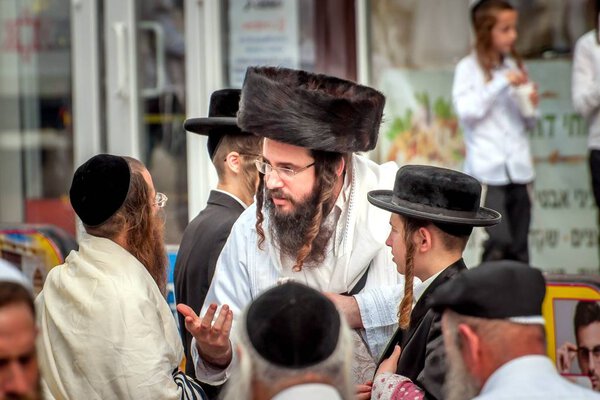 A group of Hasidim pilgrims in traditional clothing emotionally talk. Uman, Ukraine - September 21, 2017: Rosh hashanah holiday, Jewish New Year.