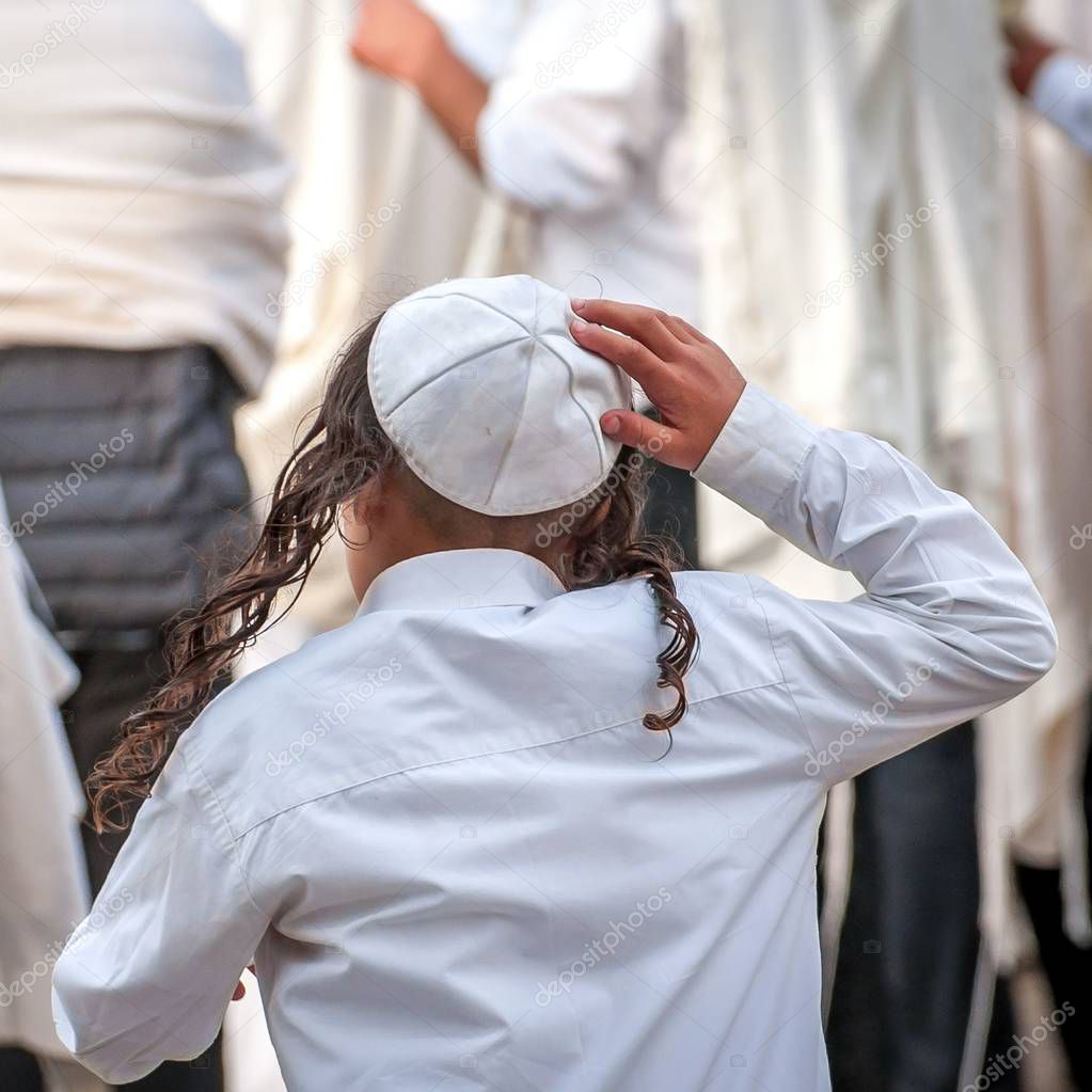 A young Jewish Hasid boy in a traditional headdress of a kippah and with long payos.