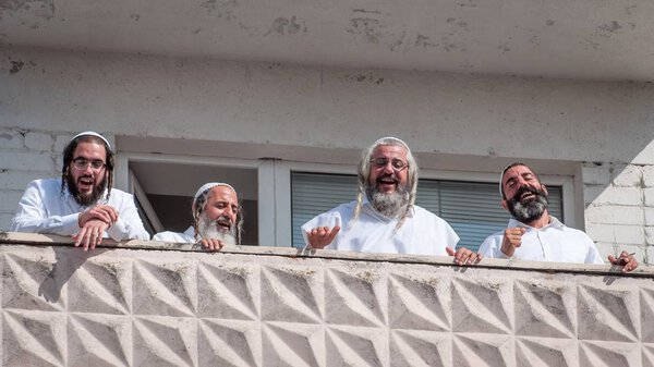 Pilgrims of Hasidi on the balcony of the high-rise building are having fun celebrating the holiday of Rosh-ha-Shana. Uman, Ukraine - September 21, 2017: Jewish New Year.