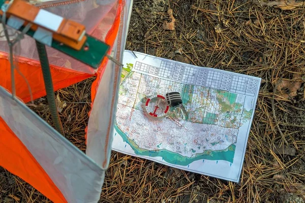 Orienteering. Compass, map, checkpoint Prism and composter for orienteering in the forest on fallen autumn needles. The concept.