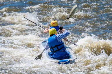 Rafting, Kayak. İki sporcu spor malzemeleri içinde kaynar su akışı bir lastik şişme botla yelken. Ekip çalışması. Su sıçramalarına yakın çekim. Aşırı spor.