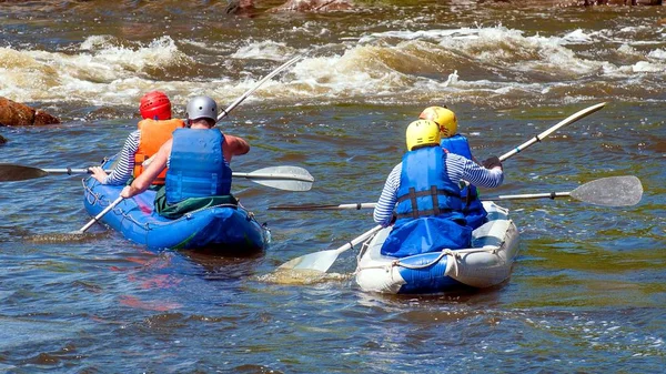 Rafting, kayaking. Athletes in sports equipment are sailing on a rubber inflatable boat in a boiling water stream. Teamwork. Water splashes close-up. Extreme sport.