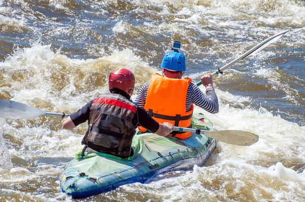 Rafting, kajakozás. Két sportolók sportfelszerelések vitorlázik a felfújható gumicsónak a forrásban lévő víz patak. Csapatmunka. Víz vízcseppek közelről. Extrém sport. — Stock Fotó