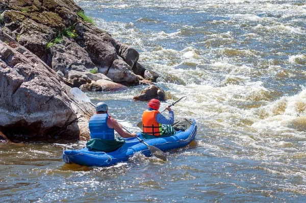 Rafting, spływy kajakowe. Dwóch sportowców w sprzęt sportowy żeglują na łodzi nadmuchiwane gumowe w strumieniu wody wrzącej. Pracy zespołowej. Zbliżenie rozpryskiwania się wody. Sport ekstremalny. — Zdjęcie stockowe